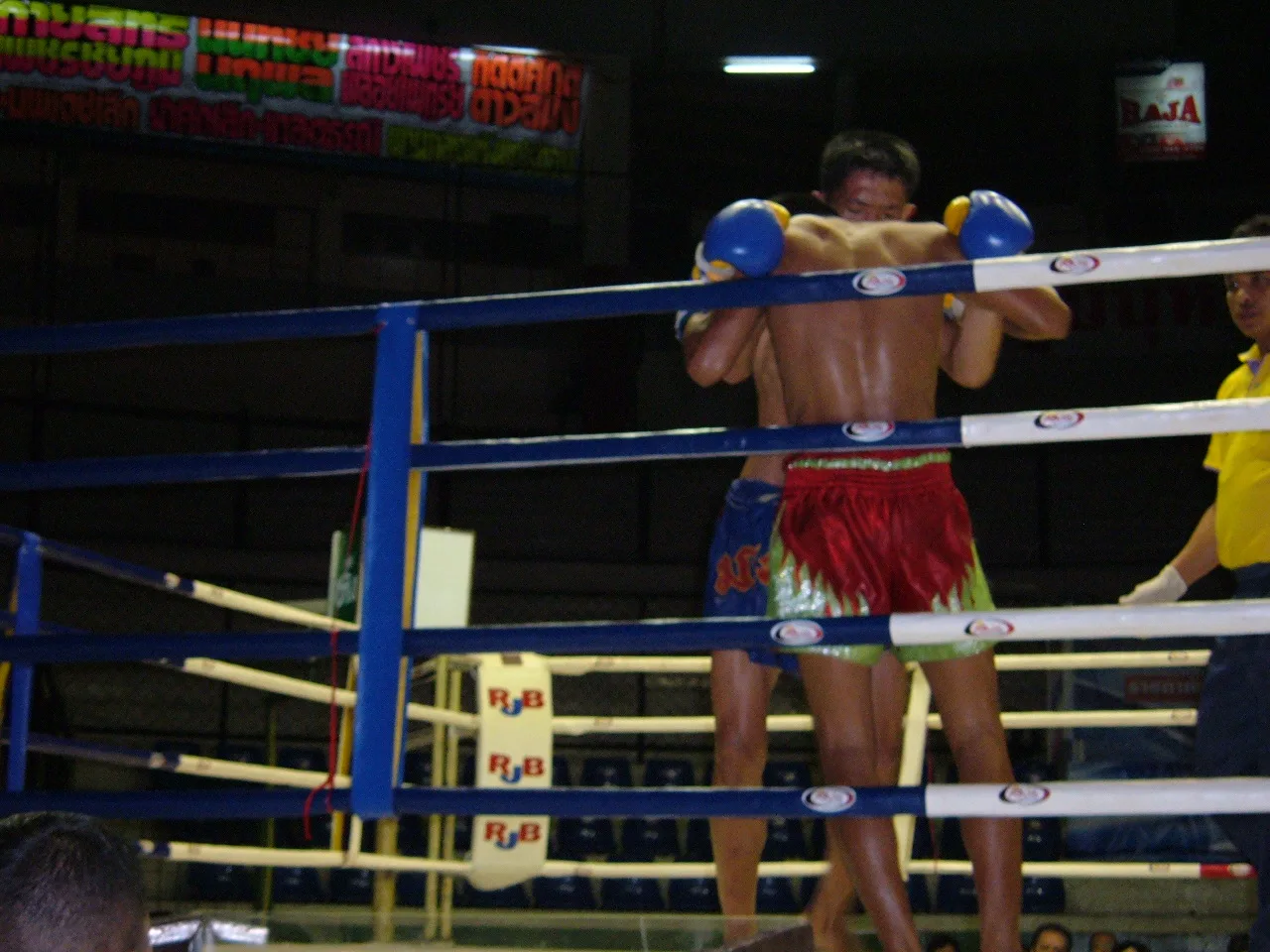 Two Muay Thai fighters clinching in the ring at Rajadamnern Stadium, Bangkok
